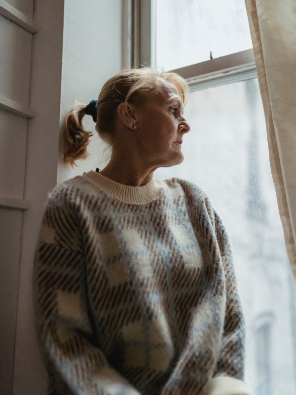 older woman looking wistfully out of a window
