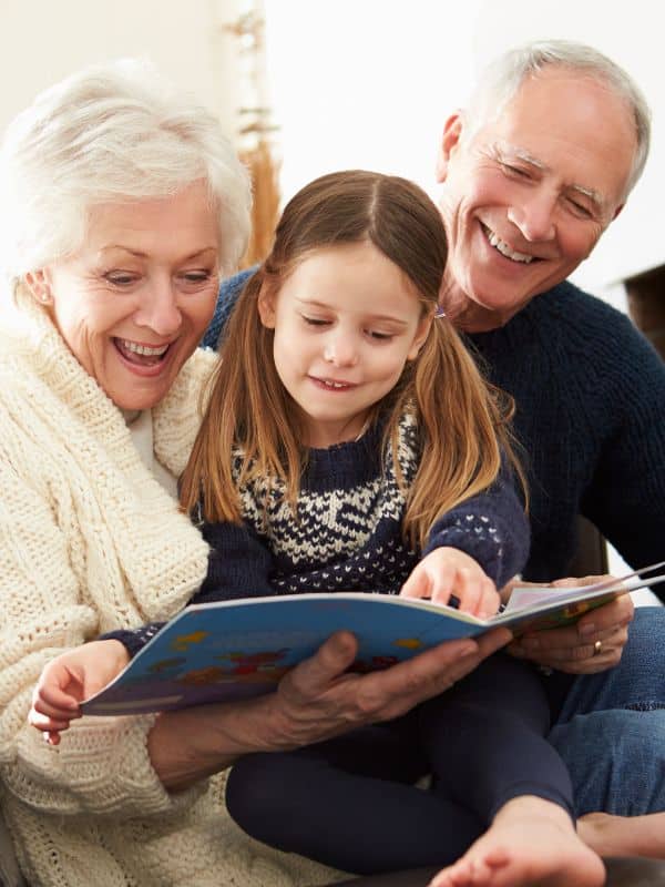 grandparents reading with their granddaughter